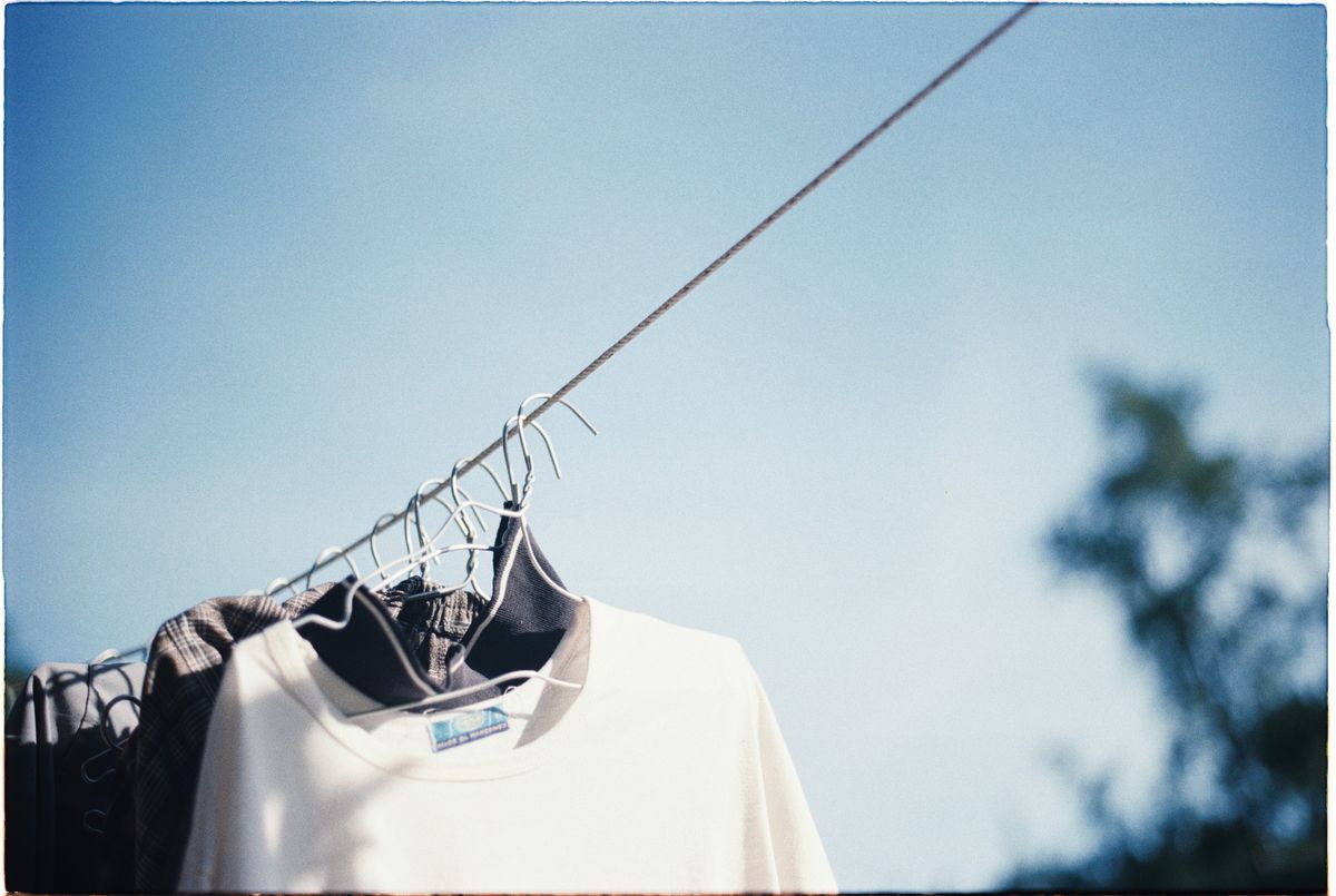 夏の青空の下、物干しワイヤーにハンガーで干された白いTシャツ